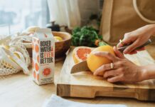 일상 속으로 스며든 웰니스 문화, 건강한 삶을 위한 작은 변화들 a person cutting an orange on a cutting board